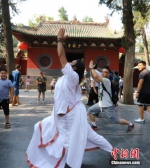 来自印度的瑜伽教练在少林寺山门展示瑜伽，吸引游客模仿学习。王中举 摄 - 中国新闻社河南分社