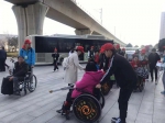图为志愿者帮助残友乘车 - 残疾人联合会