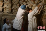 　图为博物馆的修复师在古墓里修复文物。　洛阳古代艺术博物馆供图 - 中国新闻社河南分社