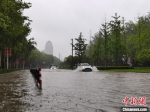 　图为7月20日上午，郑州市区，汽车在积水的道路行驶。　李贵刚 摄 - 中国新闻社河南分社