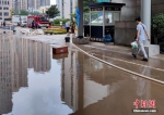 　7月22日，行人经过位于河南省郑州市的郑州大学第一附属医院河医院区的积水路面。受强降雨及院区地势低洼影响，该院受灾严重，后经院方积极应对，全院病患、医护人员已安全转运至其他院区。 中新社记者 阚力 摄 - 中国新闻社河南分社