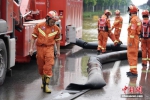 7月24日，河南新乡，无锡消防水域救援队的消防员们在新乡市主干道新中大道进行排水作业，抢通道路。图为消防员检查排水软管。 中新社记者 崔楠 摄 - 中国新闻社河南分社