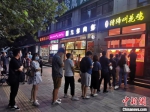 　图为8月27日晚间，郑州市民排队购买小吃，城市烟火气息渐回。　韩章云 摄 - 中国新闻社河南分社