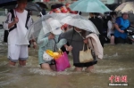 　7月20日，河南强降雨持续。图为傍晚下班时分，市民相互搀扶穿过积水的马路。中新社记者 李超庆 摄 - 中国新闻社河南分社
