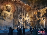 　图为游客在佛像前拍照留影。 中新社记者 刘鹏 摄 - 中国新闻社河南分社