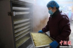 　图为1月21日，在一家制作“卷尖”的作坊，工人将制作的“卷尖”放入蒸箱蒸煮。　邓小强 摄 - 中国新闻社河南分社