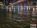 　图为积水道路段，市民涉水过马路。杨大勇 摄 - 中国新闻社河南分社