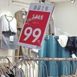 一家服装店的价格标识，“99件”旁边是手写的“起”字。 - 中国新闻社河南分社