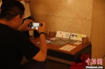 　图为一名游客拍摄活动纪念品。　阚力 摄 - 中国新闻社河南分社