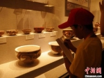 　一名海外华裔青少年在河南博物院记录馆藏彩陶器。　阚力 摄 - 中国新闻社河南分社