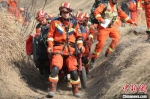 图为模拟道路受损，救援人员携带装备通过狭窄道路徒步前往震中。　李宏鹏 摄 - 中国新闻社河南分社